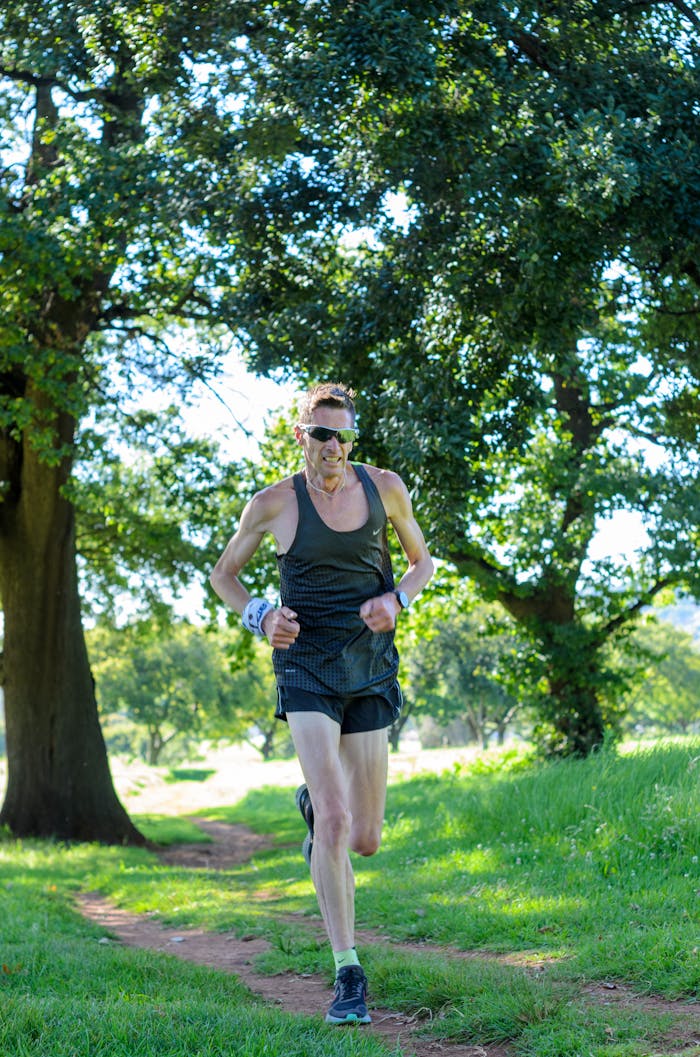 A man jogging through a forest trail, showcasing fitness and outdoor activity.