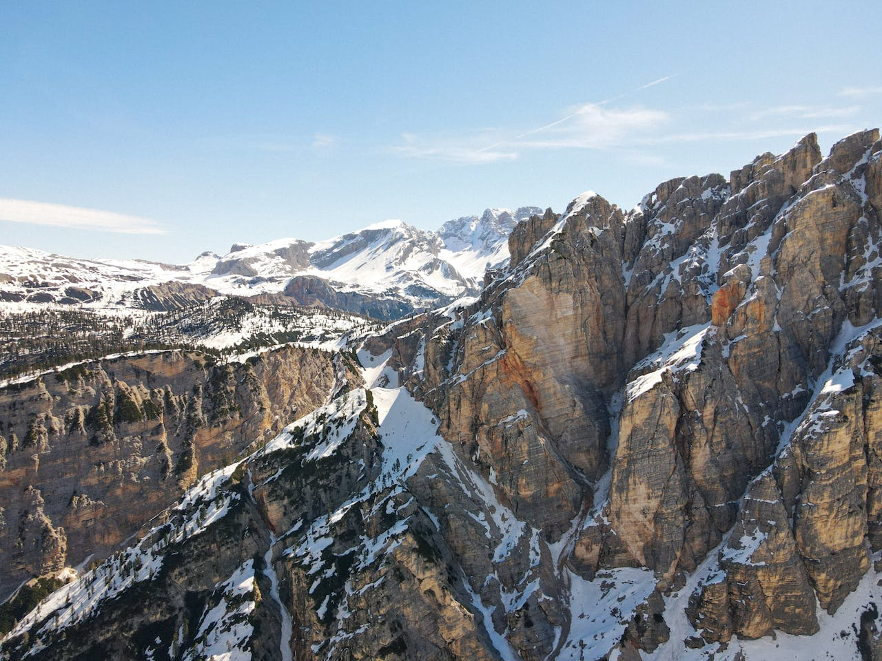 A breathtaking aerial view of snow-capped mountain peaks under a clear blue sky.